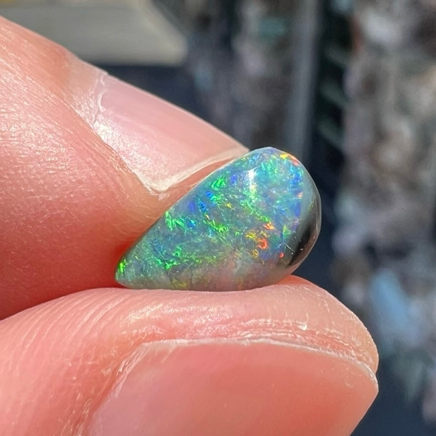 A black opal gemstone from Lightning Ridge, Australia.  The opal is a freeform cut.