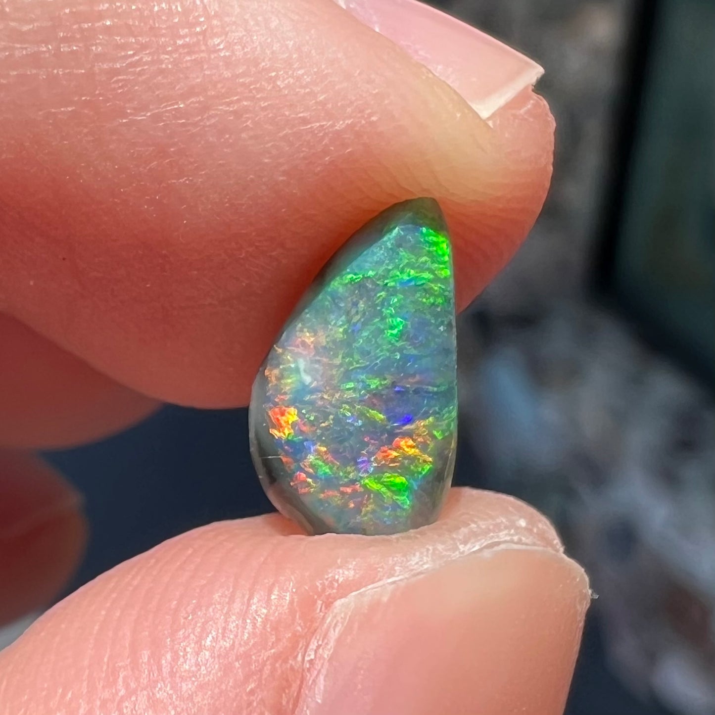 A black opal gemstone from Lightning Ridge, Australia.  The opal is a freeform cut.