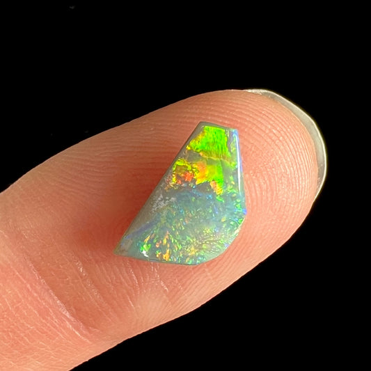 A freeform shaped semi-black opal from Lightning Ridge, Australia that weighs 1.31 carats.