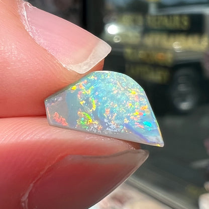 A freeform shaped semi-black opal from Lightning Ridge, Australia that weighs 1.31 carats.