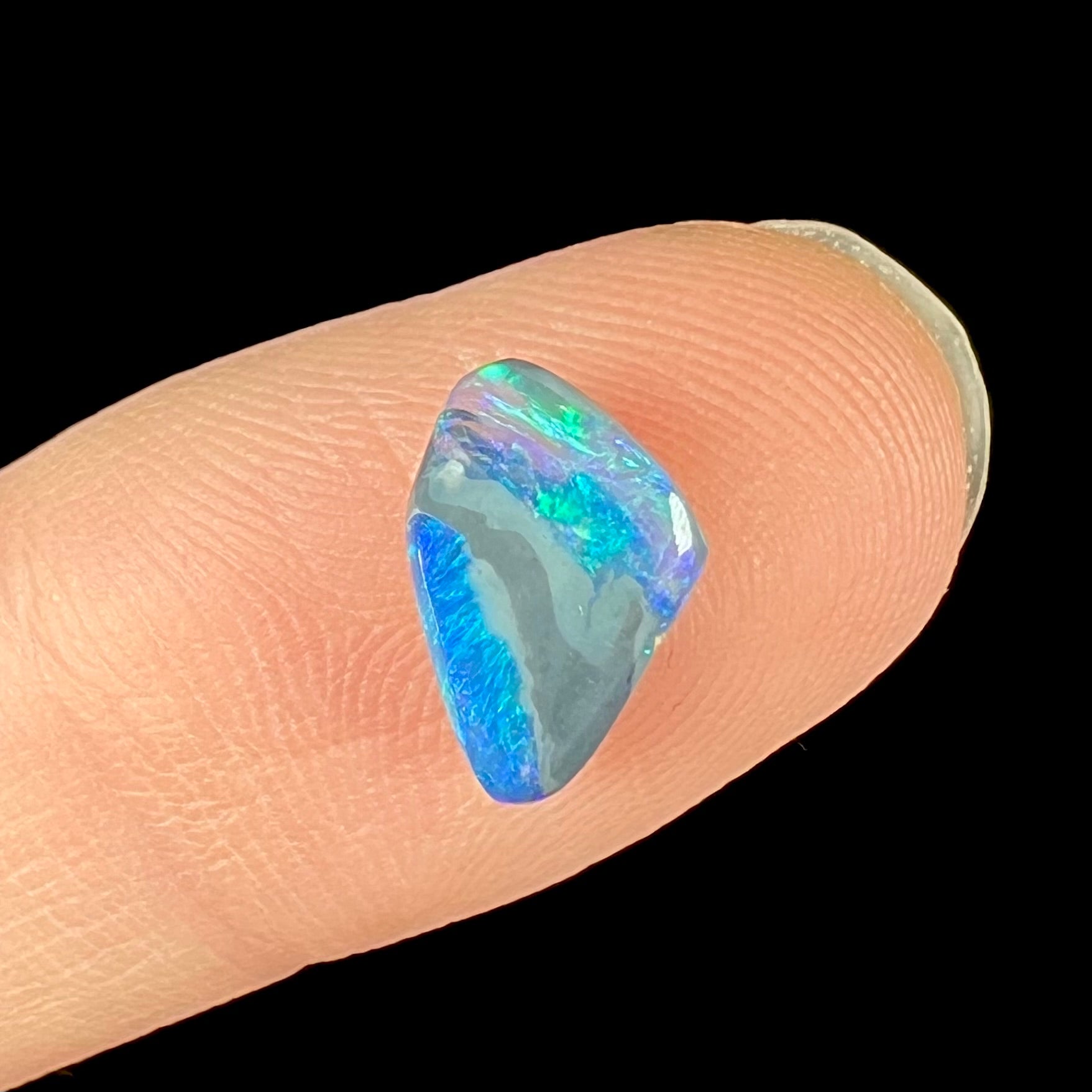 A 1.63 carat loose black opal stone from Lightning Ridge, Australia.  The opal is a freeform shape.