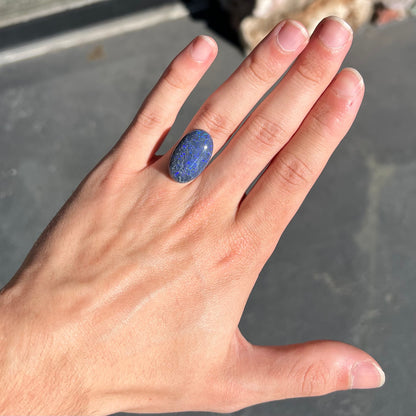 A loose, oval cabochon cut black opal from Lightning Ridge, Australia that weighs 13.09 carats.  The opal is blue.