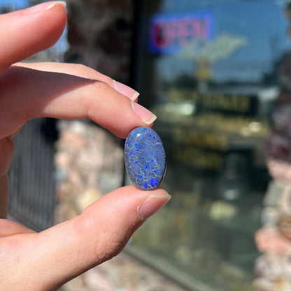 A loose, oval cabochon cut black opal from Lightning Ridge, Australia that weighs 13.09 carats.  The opal is blue.