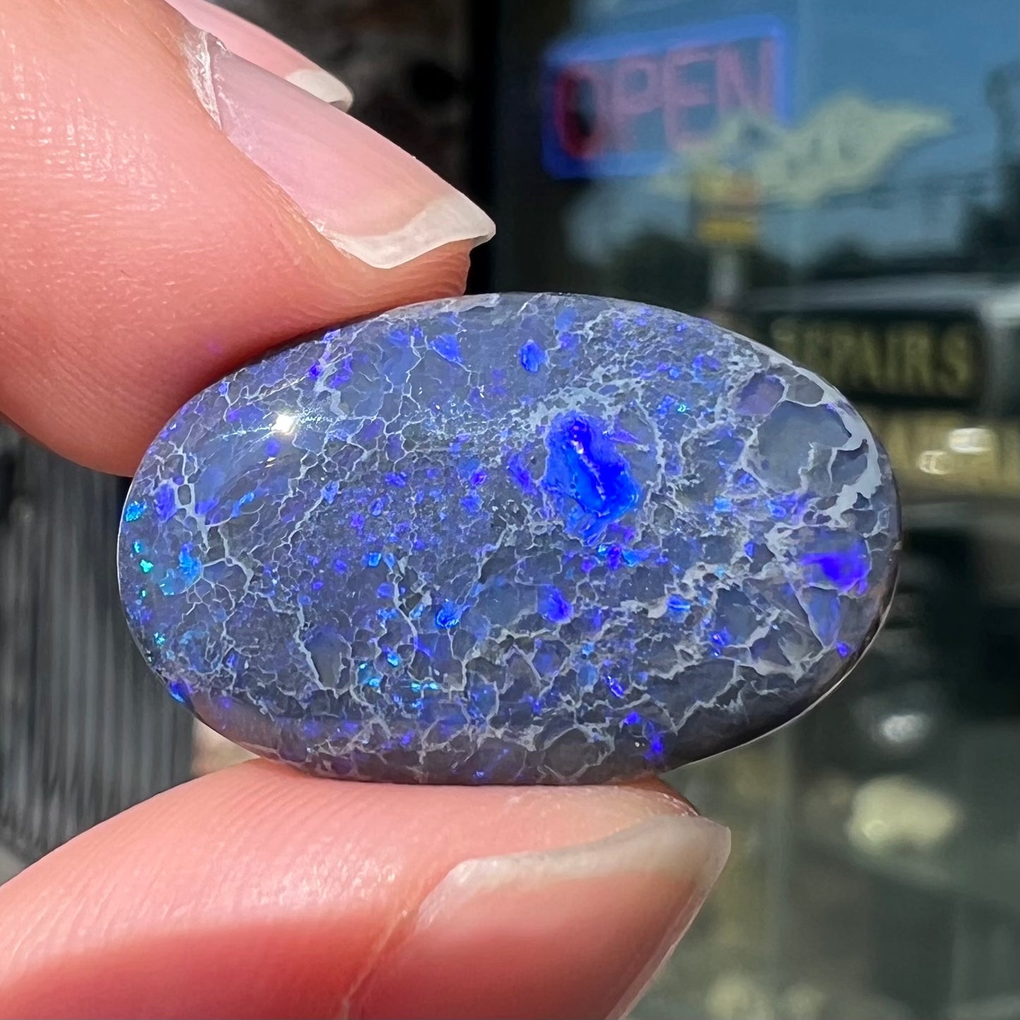 A loose, oval cabochon cut black opal from Lightning Ridge, Australia that weighs 13.09 carats.  The opal is blue.