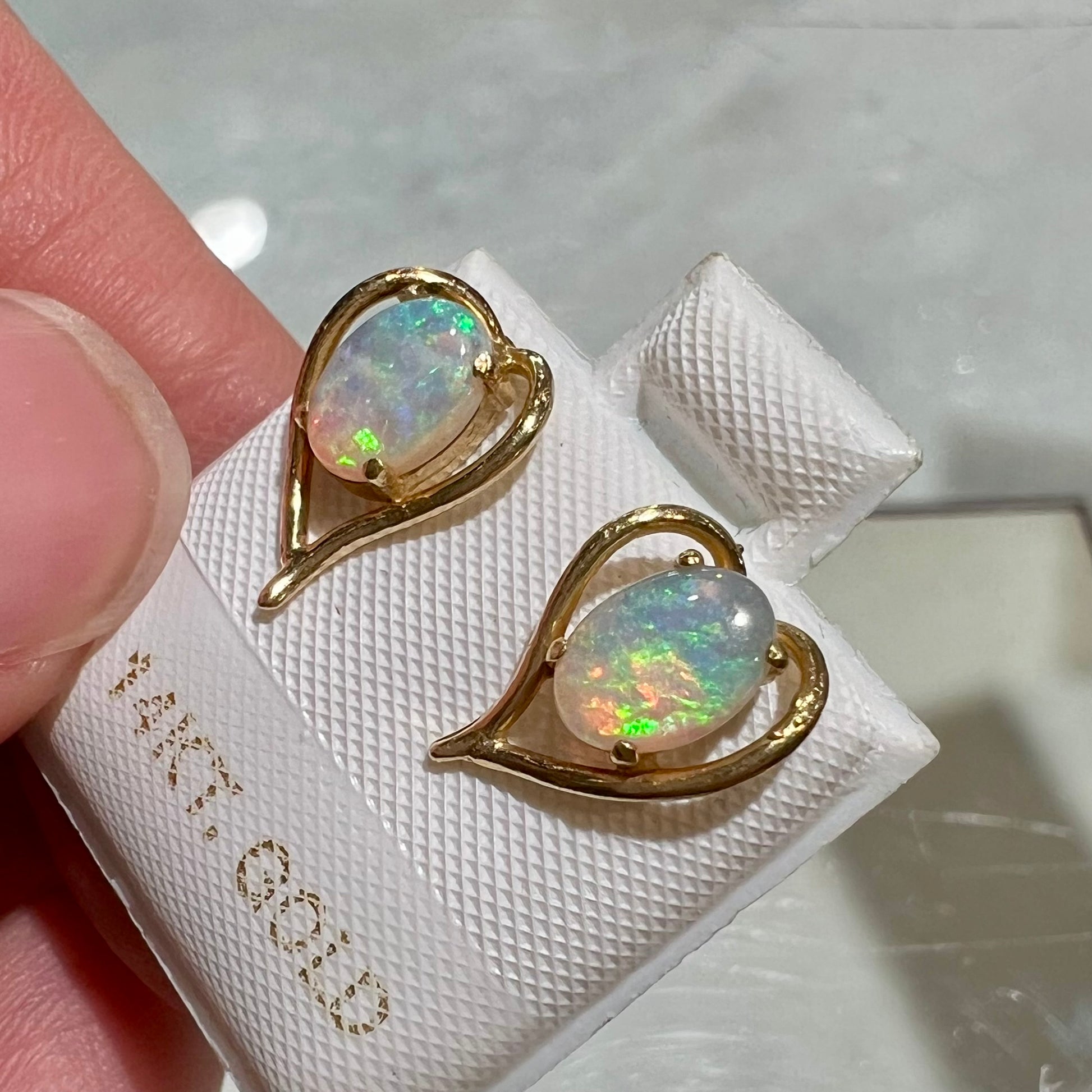 A pair of yellow gold, heart shaped stud earrings set with oval cabochon cut natural opal stones.