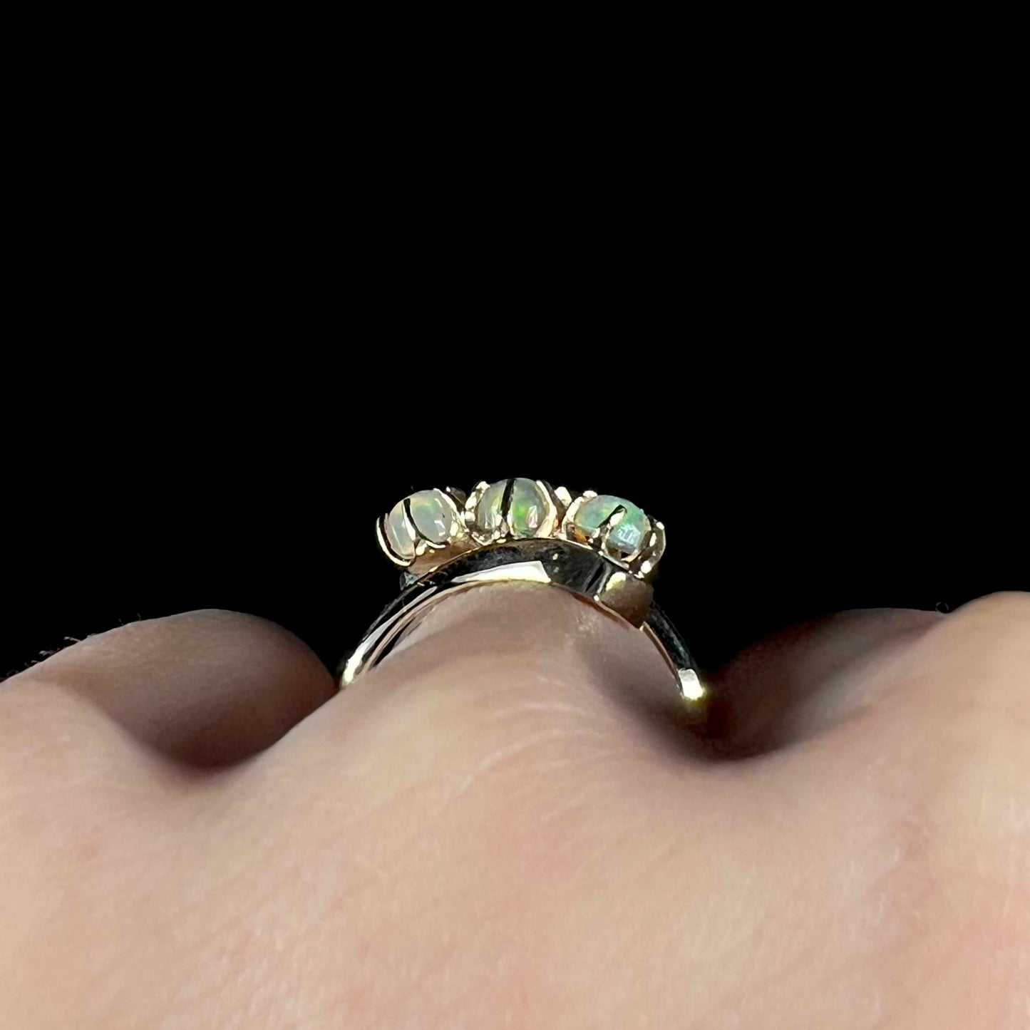 A yellow gold bypass shank ring mounted with three round cabochon cut Ethiopian fire opals.