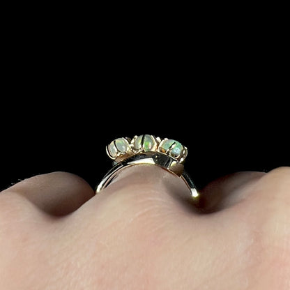 A yellow gold bypass shank ring mounted with three round cabochon cut Ethiopian fire opals.