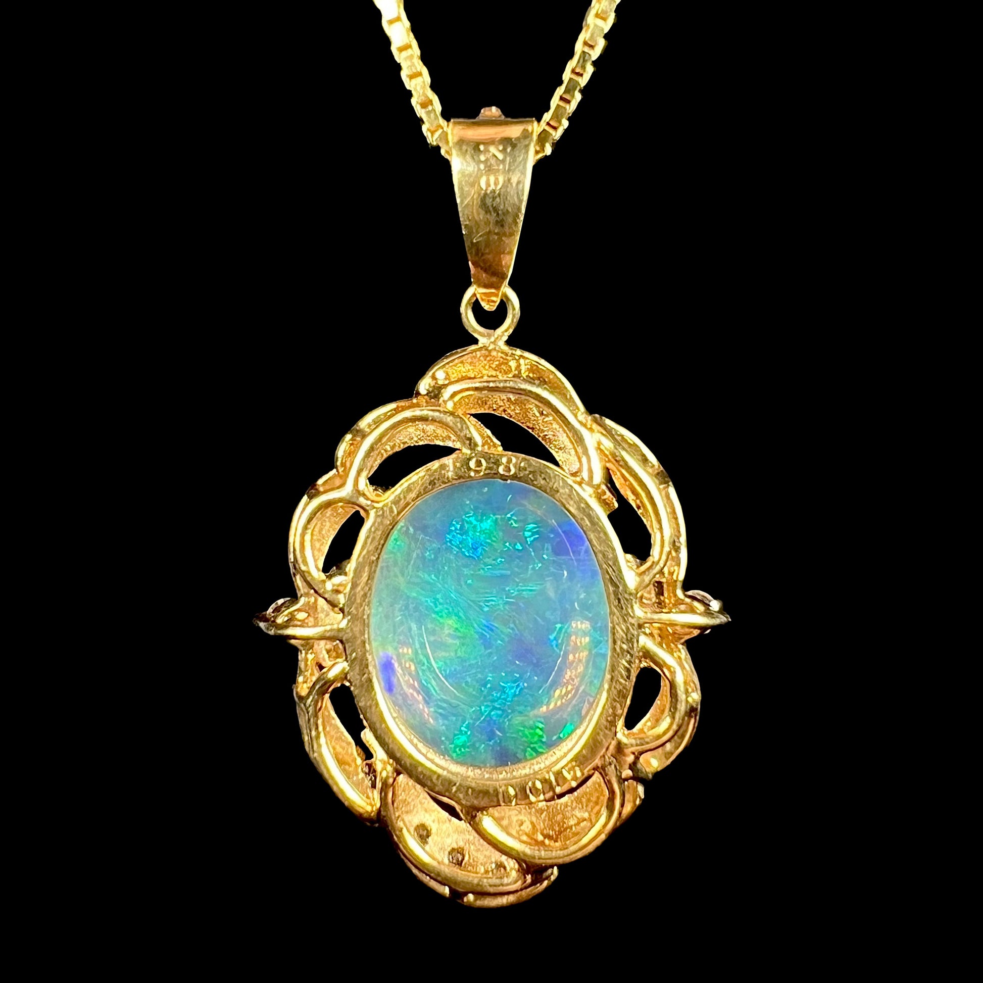 An 18 karat yellow gold diamond-accented necklace mounted with a green and blue Lightning Ridge crystal opal.