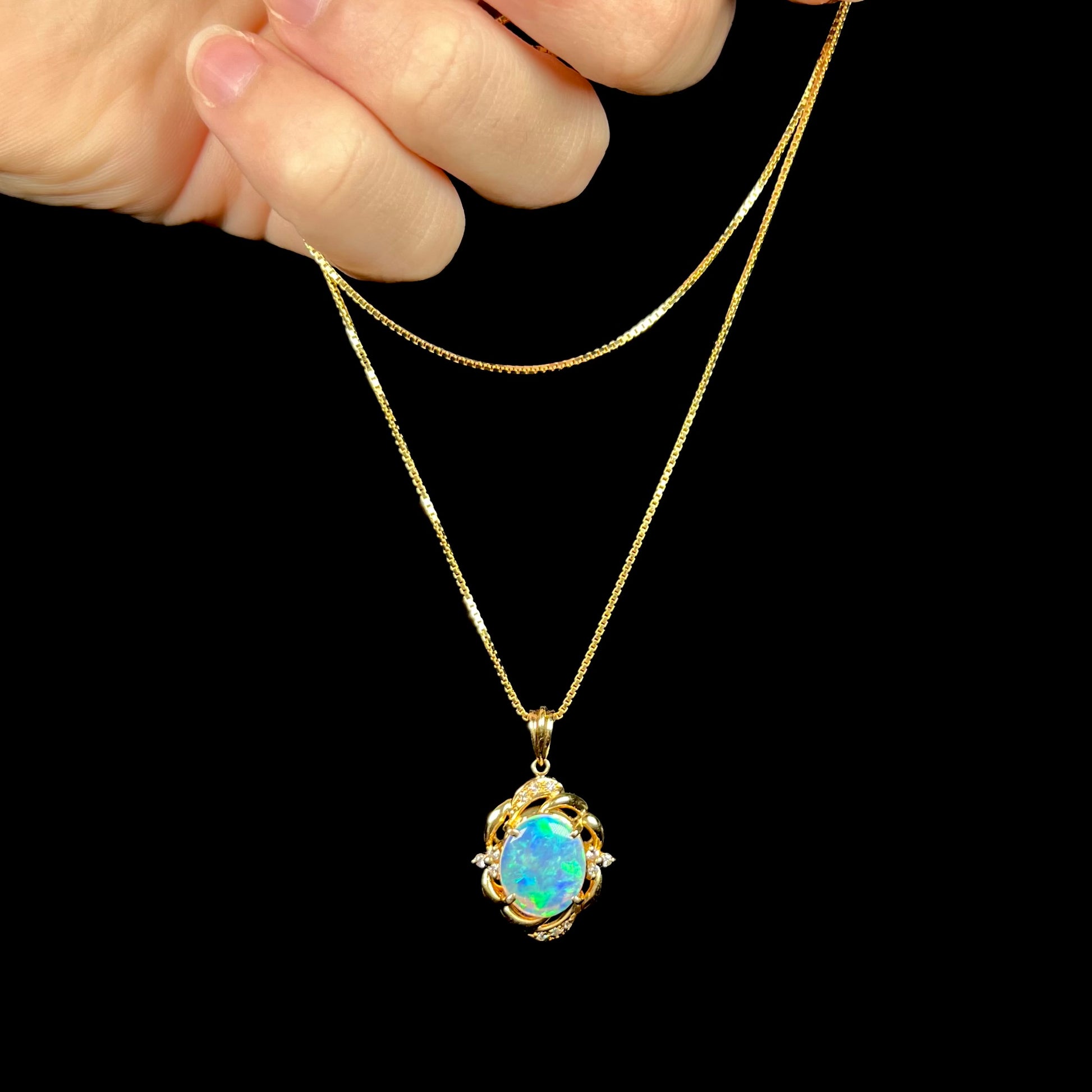 An 18 karat yellow gold diamond-accented necklace mounted with a green and blue Lightning Ridge crystal opal.