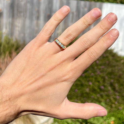 An 18 karat yellow gold line-style filigree ring mounted with five round, cabochon cut Australian crystal opals.