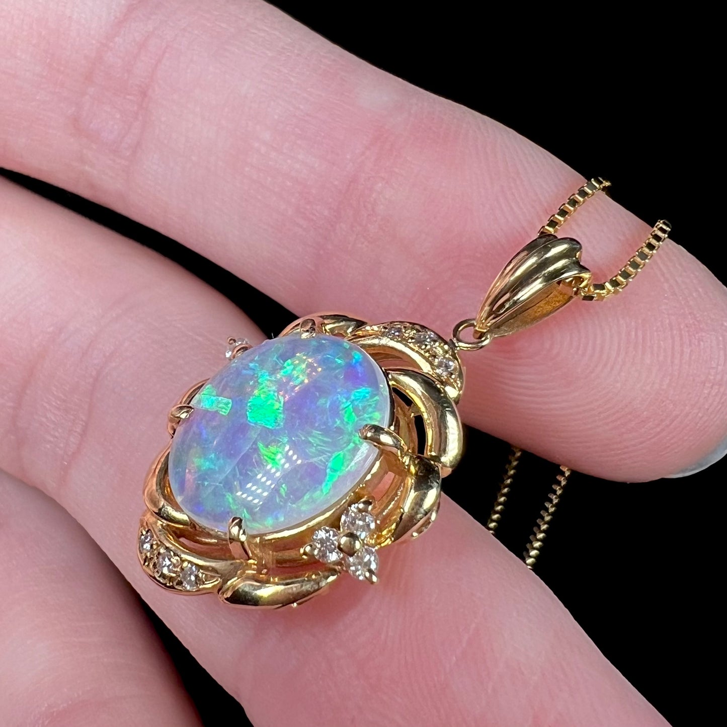 An 18 karat yellow gold diamond-accented necklace mounted with a green and blue Lightning Ridge crystal opal.