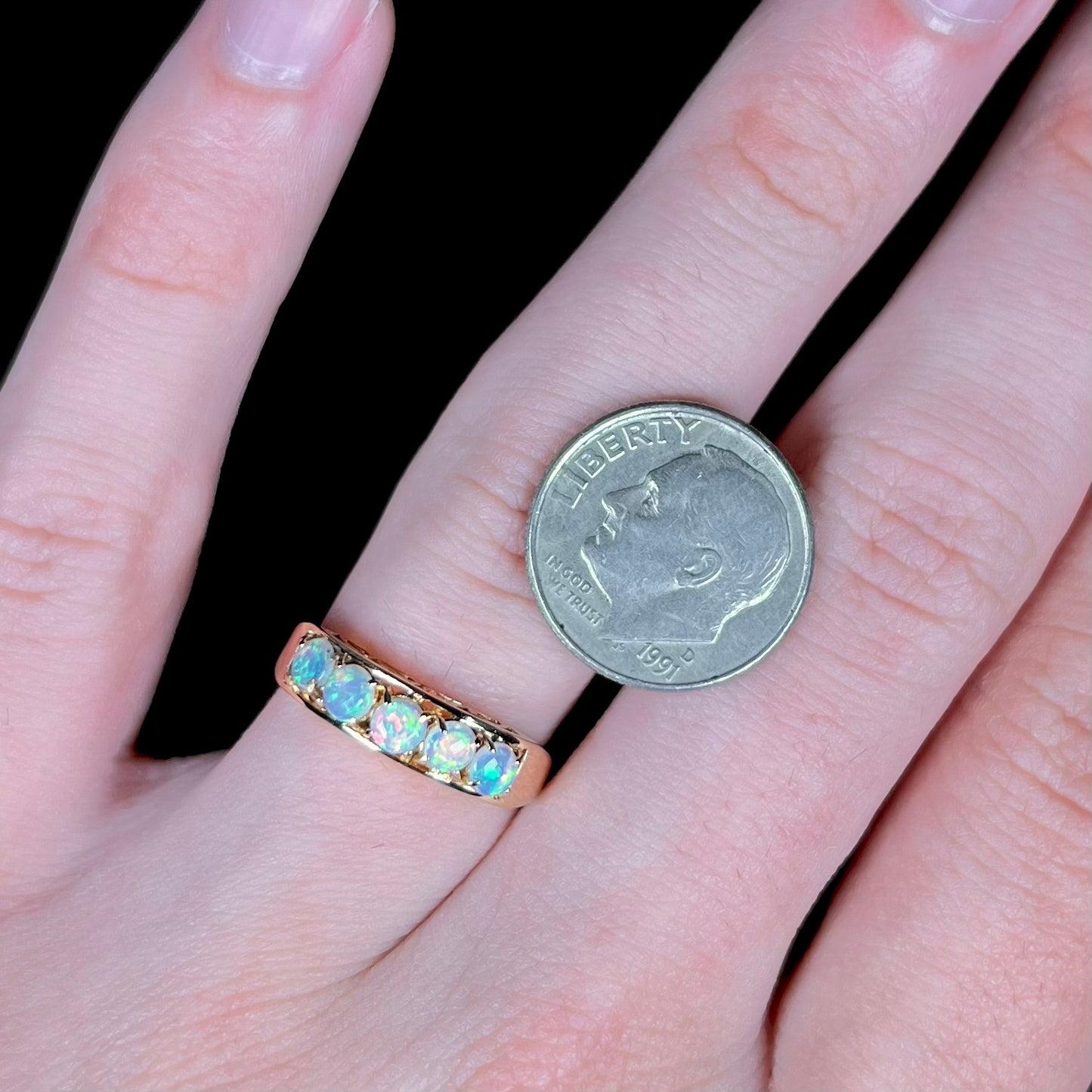 An 18 karat yellow gold line-style filigree ring mounted with five round, cabochon cut Australian crystal opals.