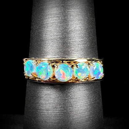 An 18 karat yellow gold line-style filigree ring mounted with five round, cabochon cut Australian crystal opals.