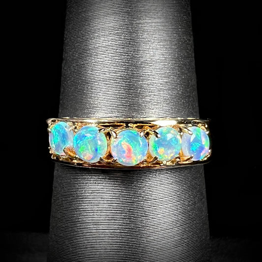 An 18 karat yellow gold line-style filigree ring mounted with five round, cabochon cut Australian crystal opals.