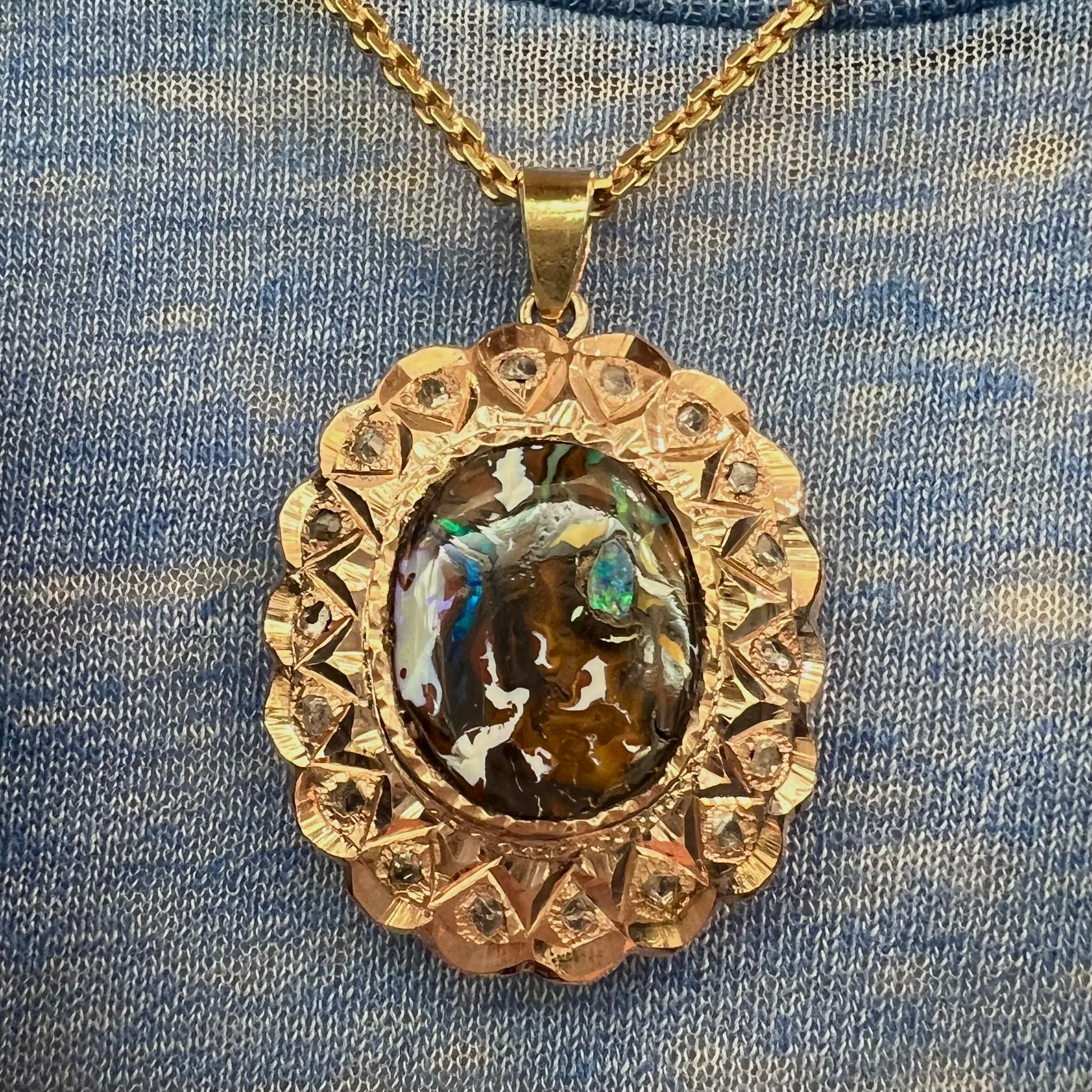 An antique 18 karat yellow gold pendant set with rough diamonds and an oval cut boulder opal from Koroit, Australia.