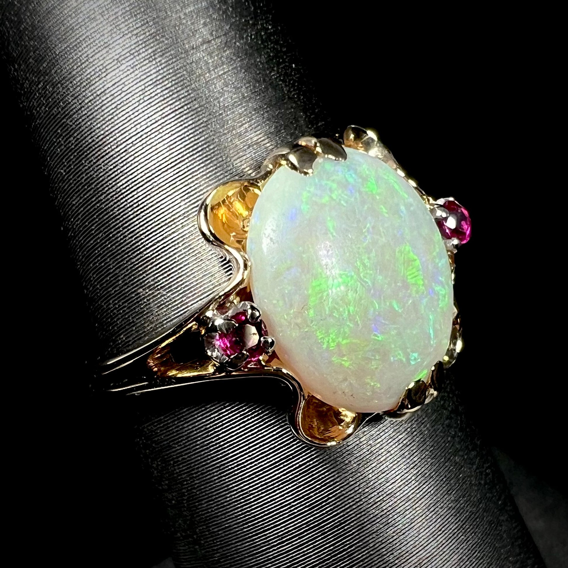 A 1920's Art Nouveau opal and pink sapphire ring.   The ring is yellow gold and palladium.  The opal is green and purple.