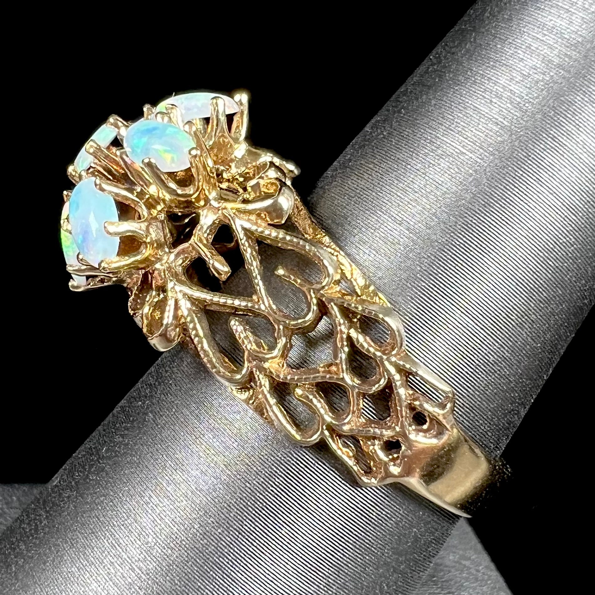 A vintage, 1950's style opal cluster ring cast in yellow gold with a heart shaped filigree design.