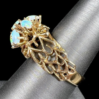 A vintage, 1950's style opal cluster ring cast in yellow gold with a heart shaped filigree design.