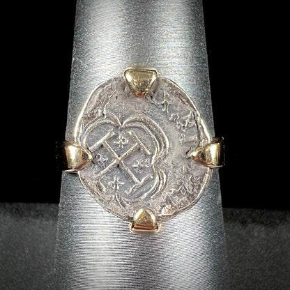 A silver Atocha 1 reale coin replica set in a yellow gold ring.