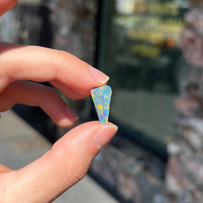 A loose, freeform triangle shaped black opal stone from Lightning Ridge, Australia that weighs 2.71 carats.