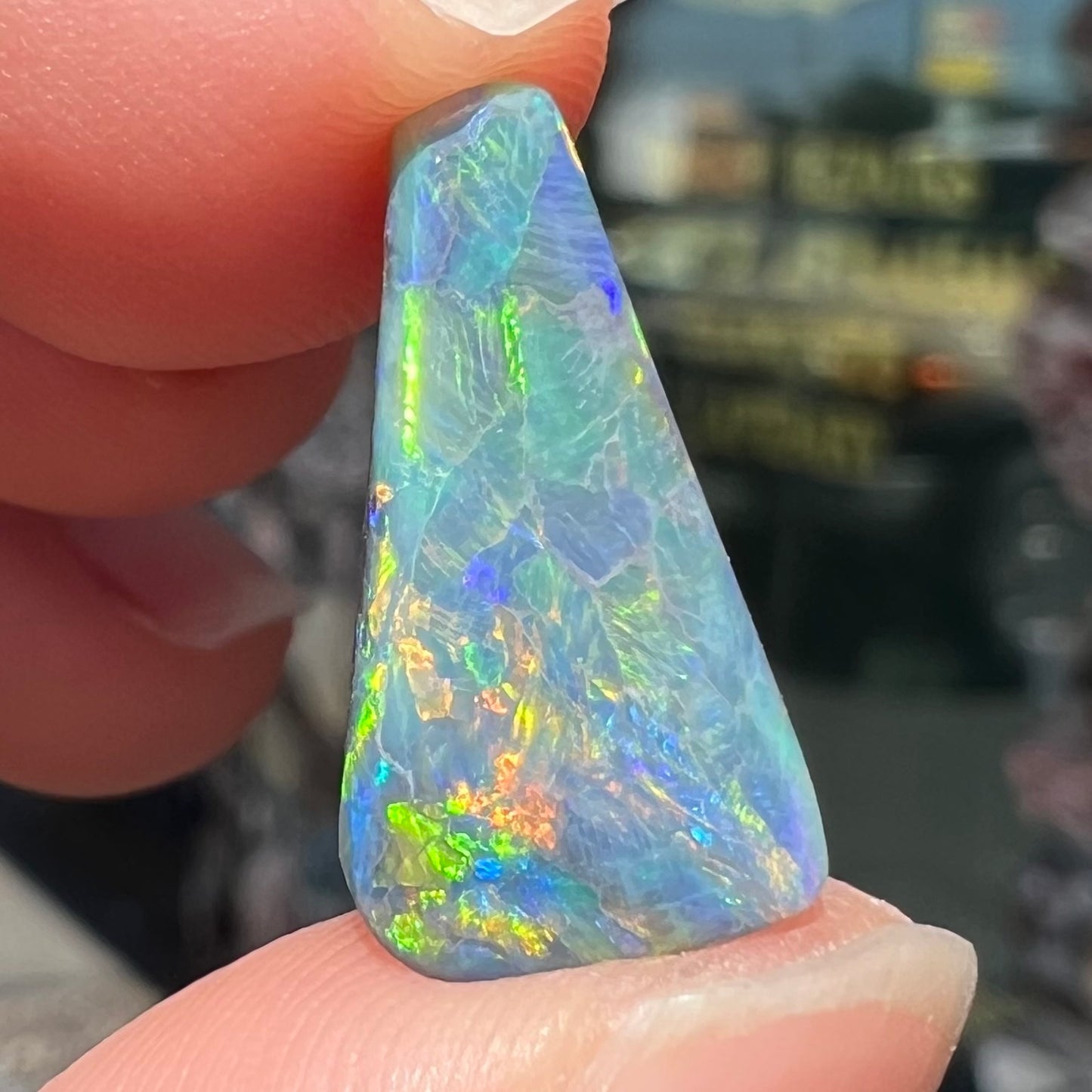 A loose, freeform triangle shaped black opal stone from Lightning Ridge, Australia that weighs 2.71 carats.