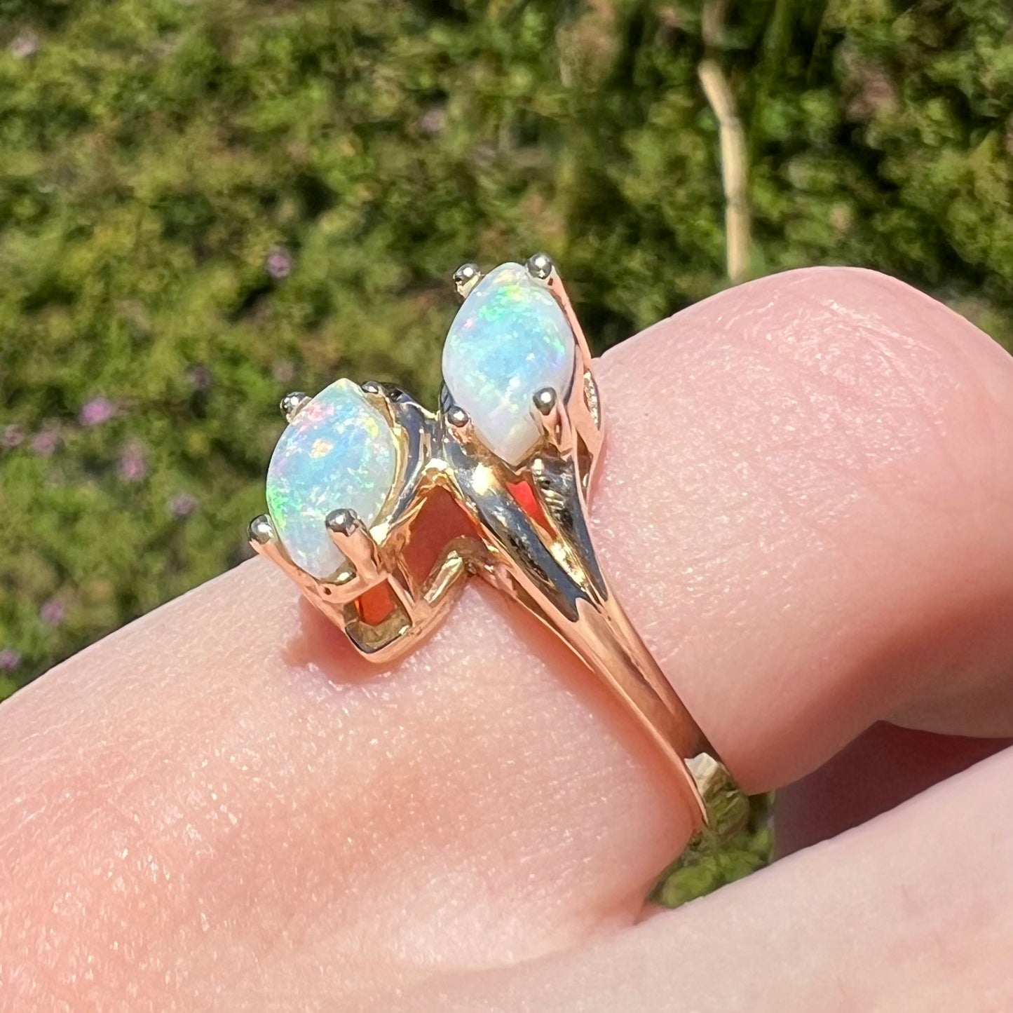 A yellow gold ring mounted with two prong-set marquise cut opal cabochons.