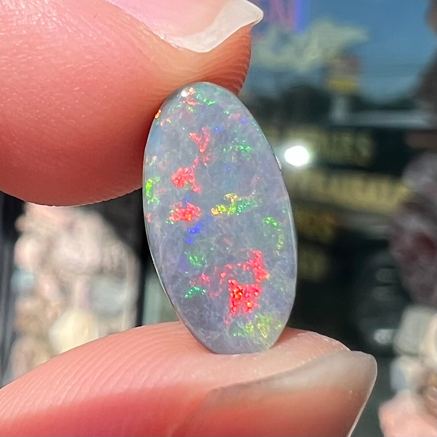 A loose, 3.01 carat, oval cut semi-black opal stone from Lightning Ridge, Australia.  The opal has red colors.