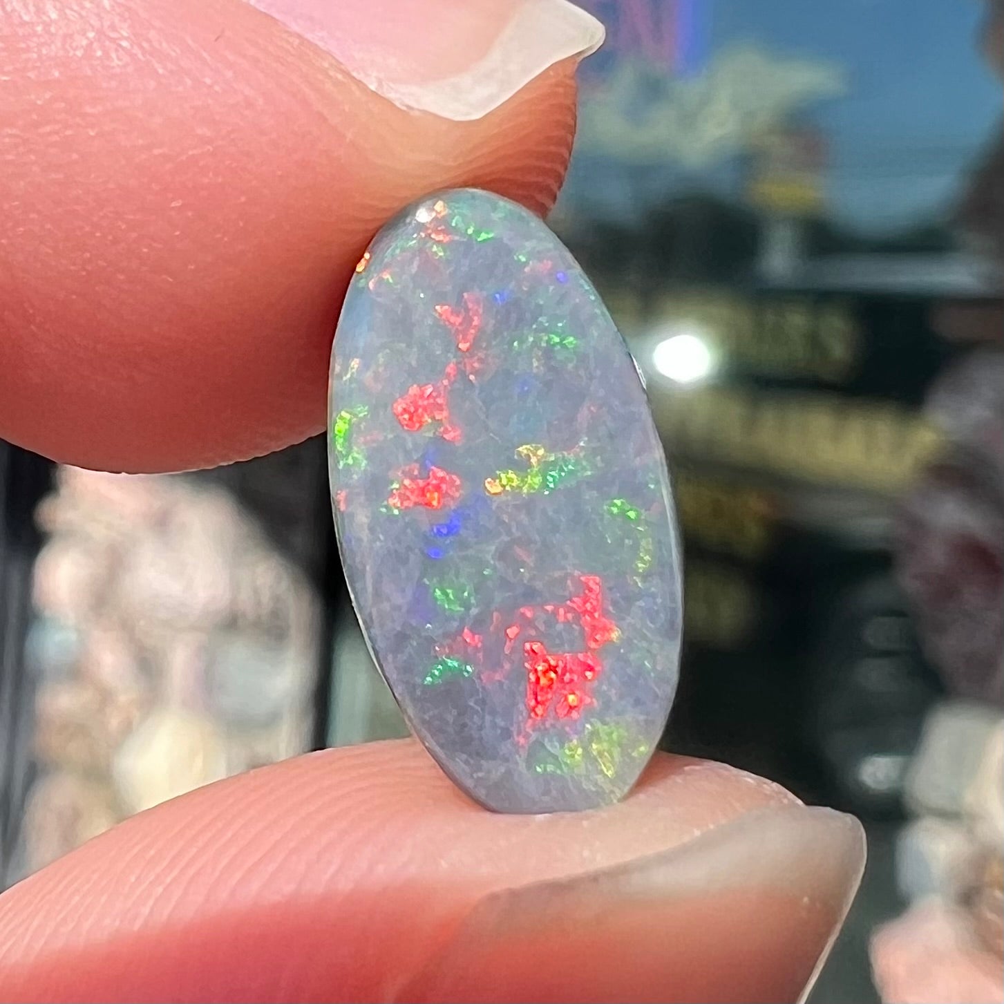 A loose, 3.01 carat, oval cut semi-black opal stone from Lightning Ridge, Australia.  The opal has red colors.