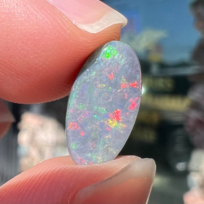 A loose, 3.01 carat, oval cut semi-black opal stone from Lightning Ridge, Australia.  The opal has red colors.