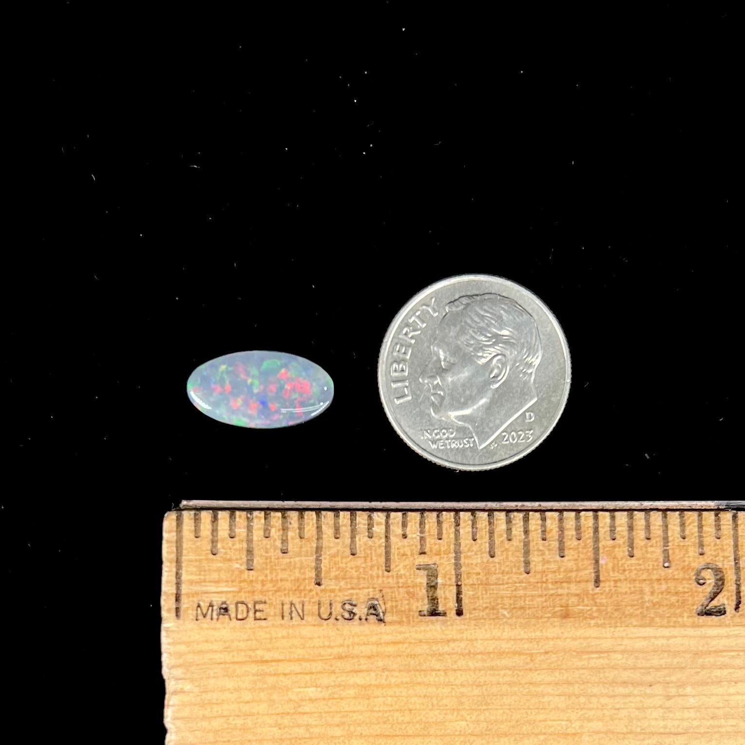 A loose, 3.01 carat, oval cut semi-black opal stone from Lightning Ridge, Australia.  The opal has red colors.