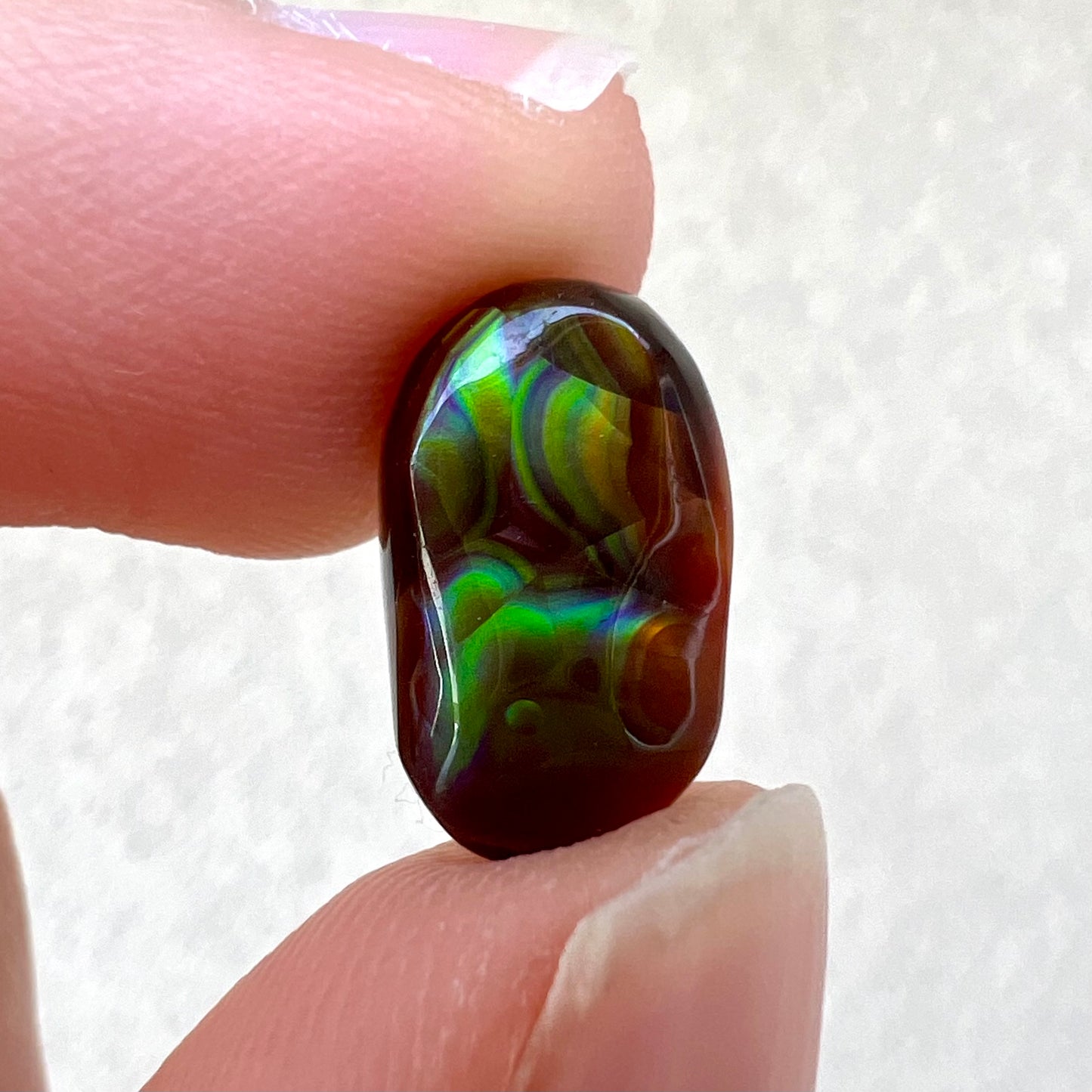 A loose, oval cabochon cut Mexican fire agate stone.  The stone has multi-colored banding with blue overtones.