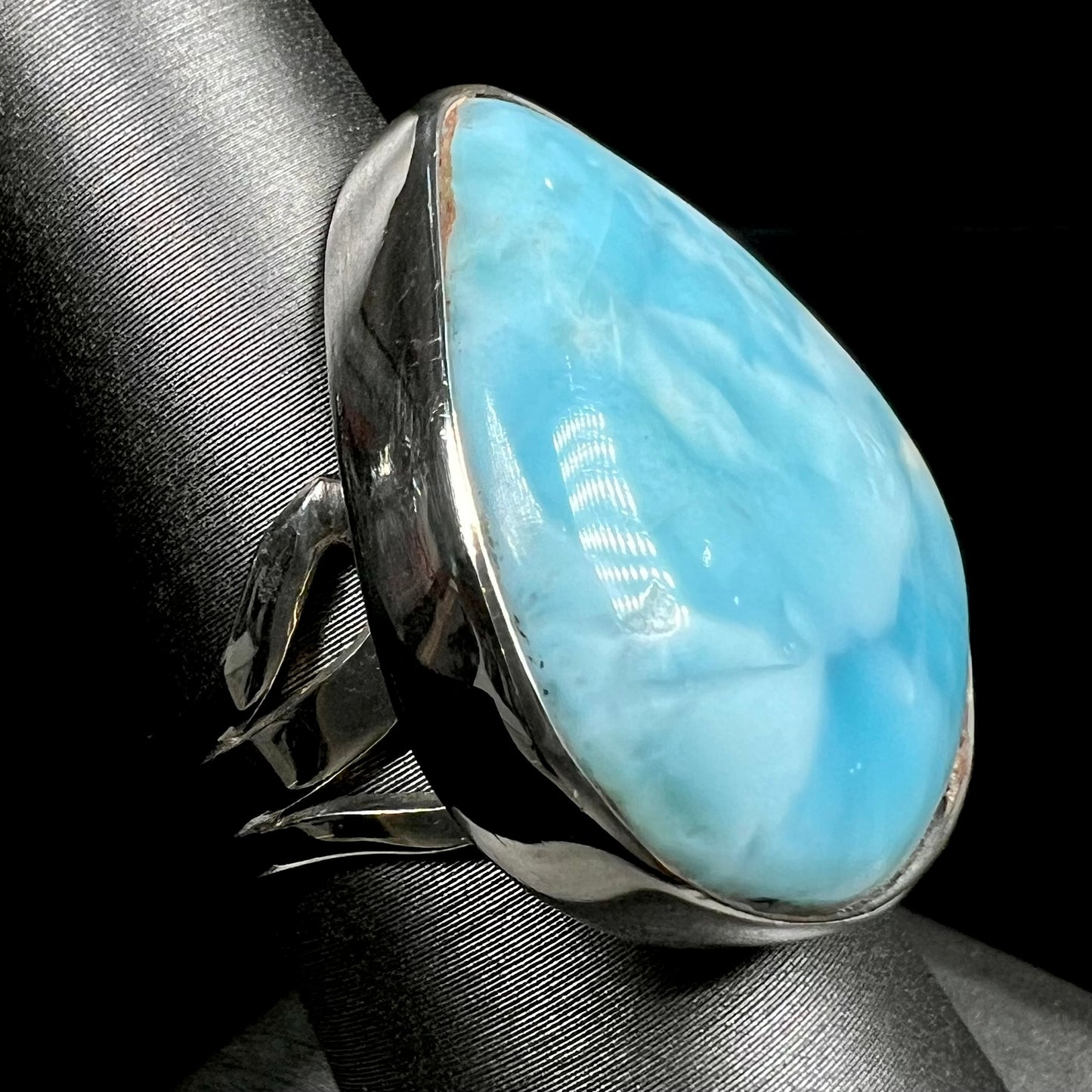 A ladies' large, pear shaped larimar solitaire ring in sterling silver.  The larimar stone measures an inch long.