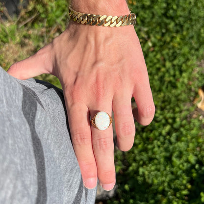 A yellow gold solitaire cocktail ring mounted with a natural white opal from Coober Pedy, Australia.