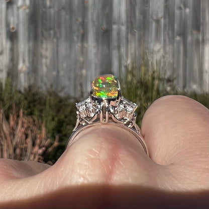 A platinum filigree ring mounted with a high-domed Mexican fire opal and baguette cut diamond accents.