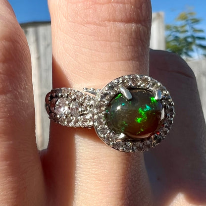 A CZ-accented sterling silver halo ring mounted with a smoked Ethiopian fire opal.  The opal plays green, red, and blue colors.