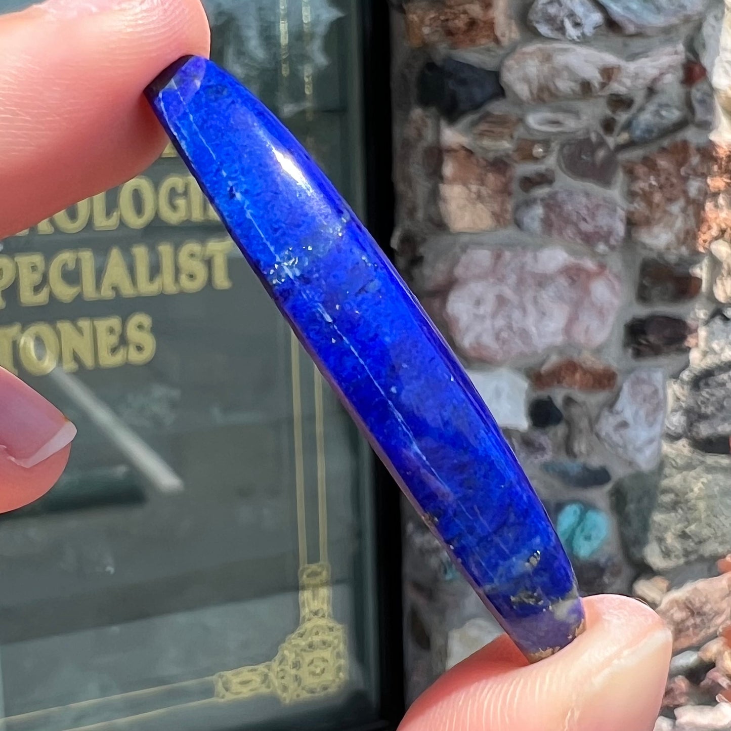 A loose, marquise cabochon cut lapis lazuli stone.  The stone has pyrite inclusions.