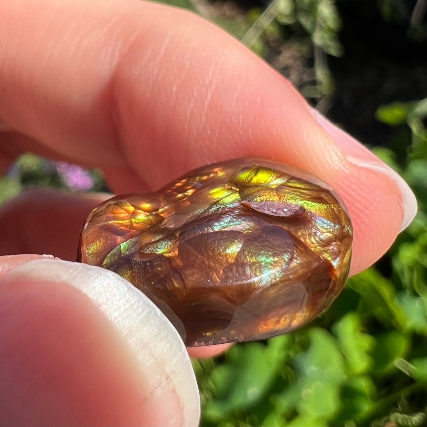 An oval cabochon cut Mexican fire agate stone.  The stone's predominant colors are green, yellow, orange, and blue.