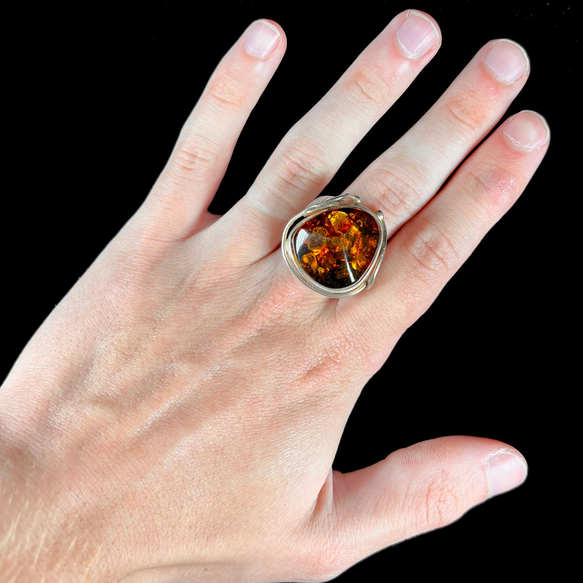 Unisex sterling silver ring set with a large sun-spangled Baltic amber gemstone.