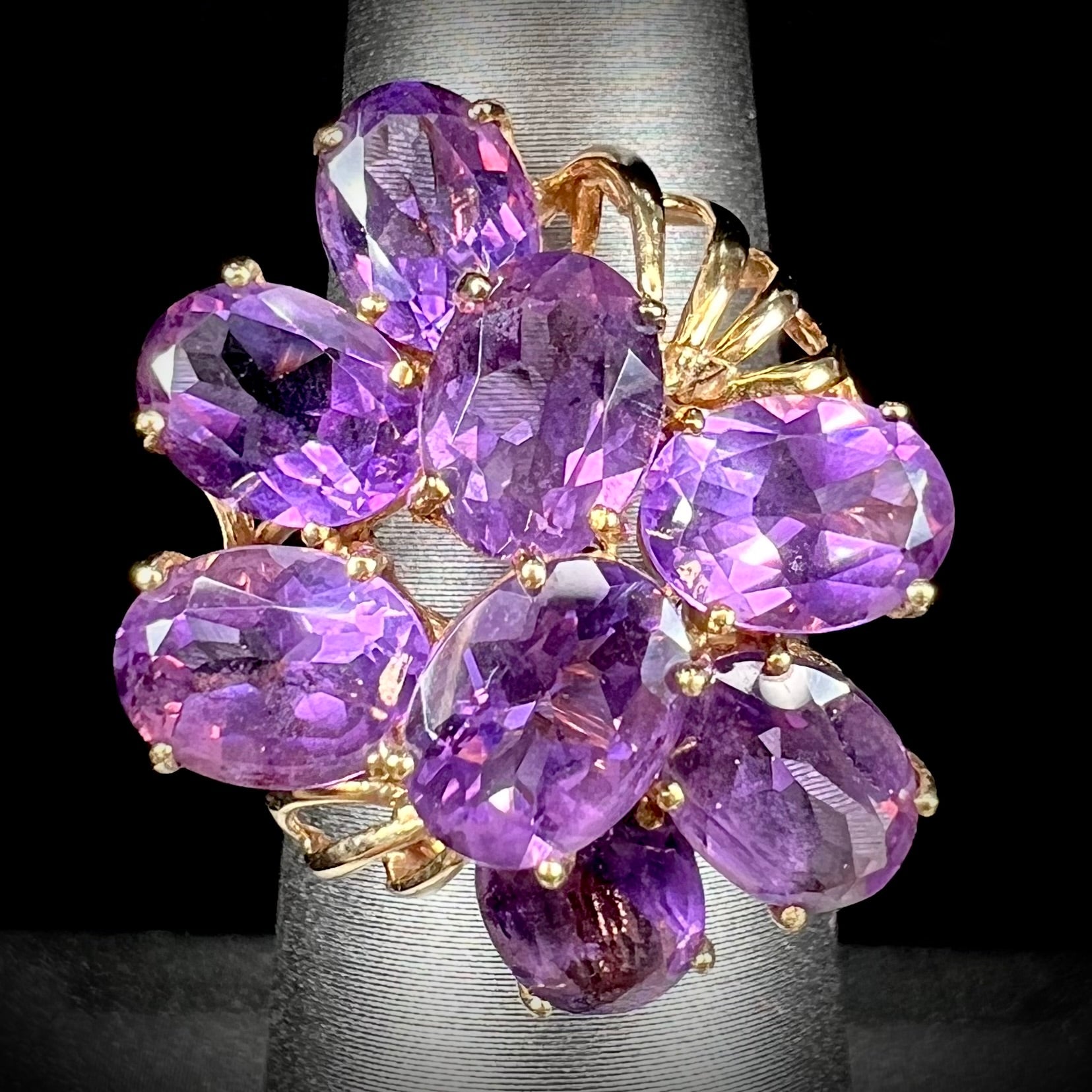 A cluster ring set with eight purple oval cut amethysts in yellow gold.