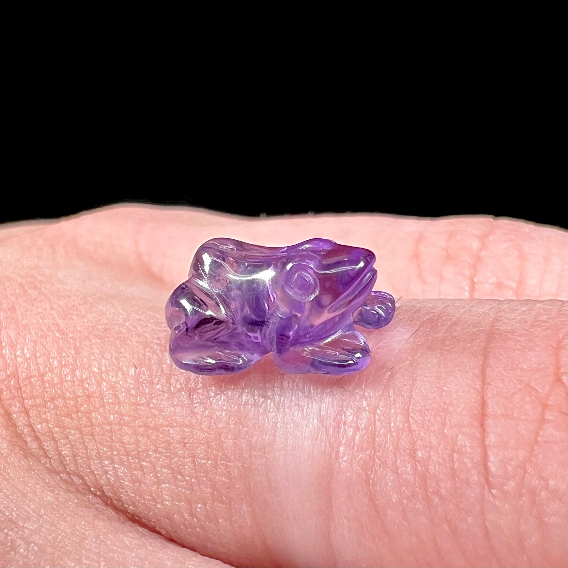 A stone frog carved from purple amethyst crystal.