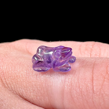 A stone frog carved from purple amethyst crystal.