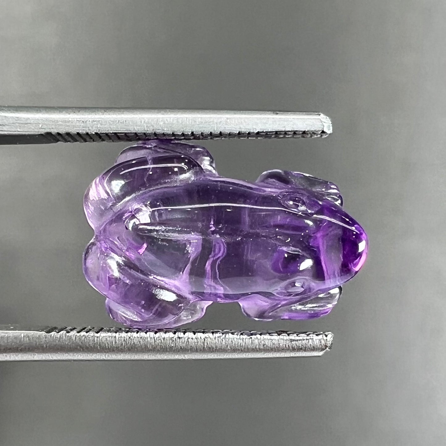 A stone frog carved from purple amethyst crystal.