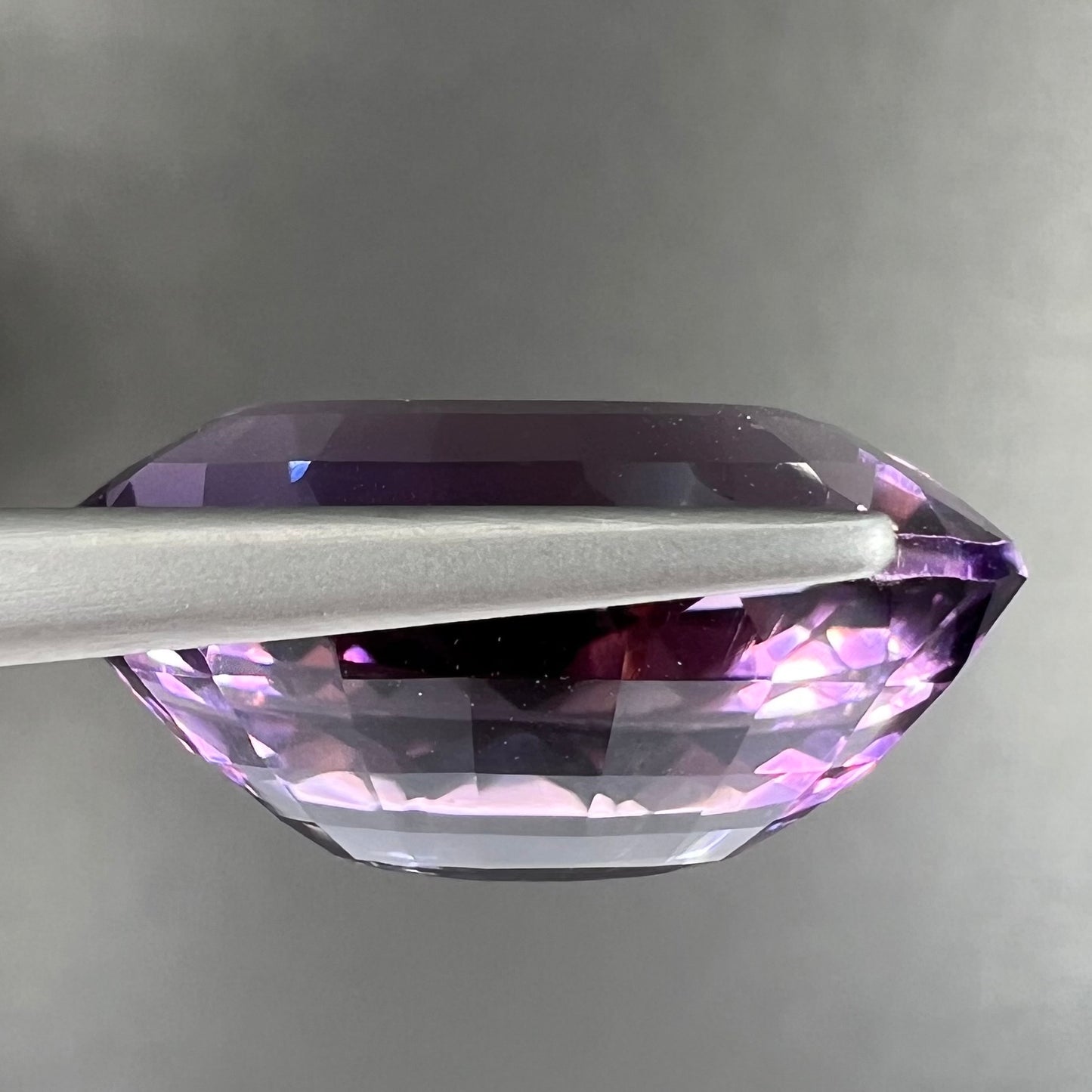 A loose, modified oval step cut amethyst gemstone.  There are light scratches to the table.