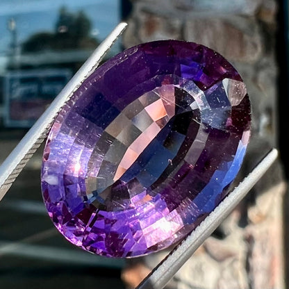 A loose, modified oval step cut amethyst gemstone.  There are light scratches to the table.