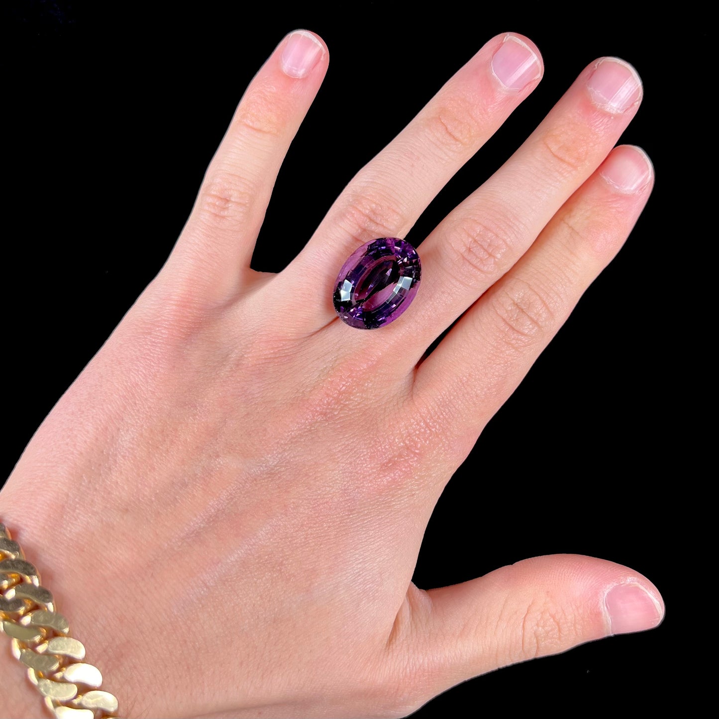 A loose, modified oval step cut amethyst gemstone.  There are light scratches to the table.