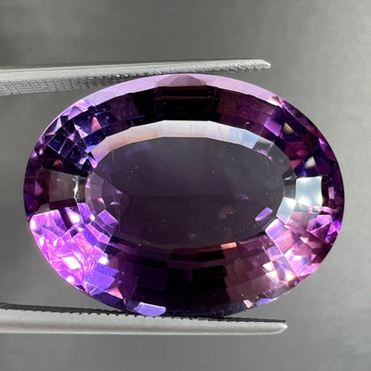 A loose, modified oval step cut amethyst gemstone.  There are light scratches to the table.