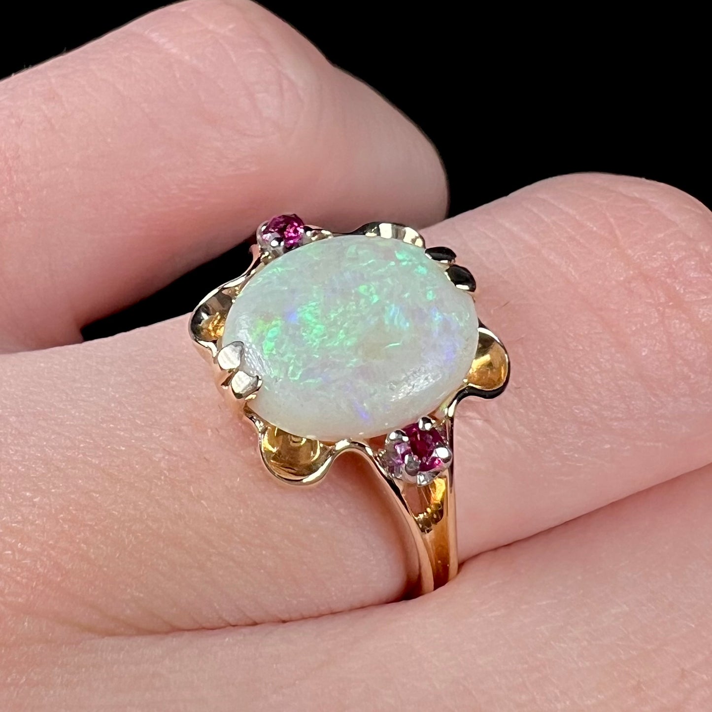 A 1920's Art Nouveau opal and pink sapphire ring.   The ring is yellow gold and palladium.  The opal is green and purple.