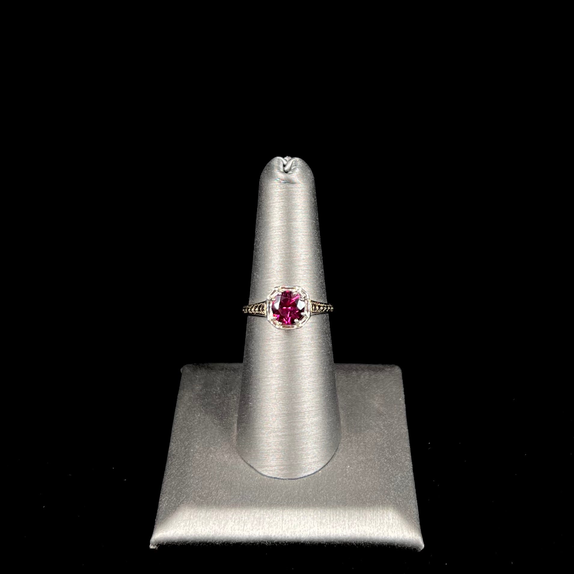 A ladies' yellow gold Art Deco style solitaire ring set with a purple rhodolite garnet gemstone.