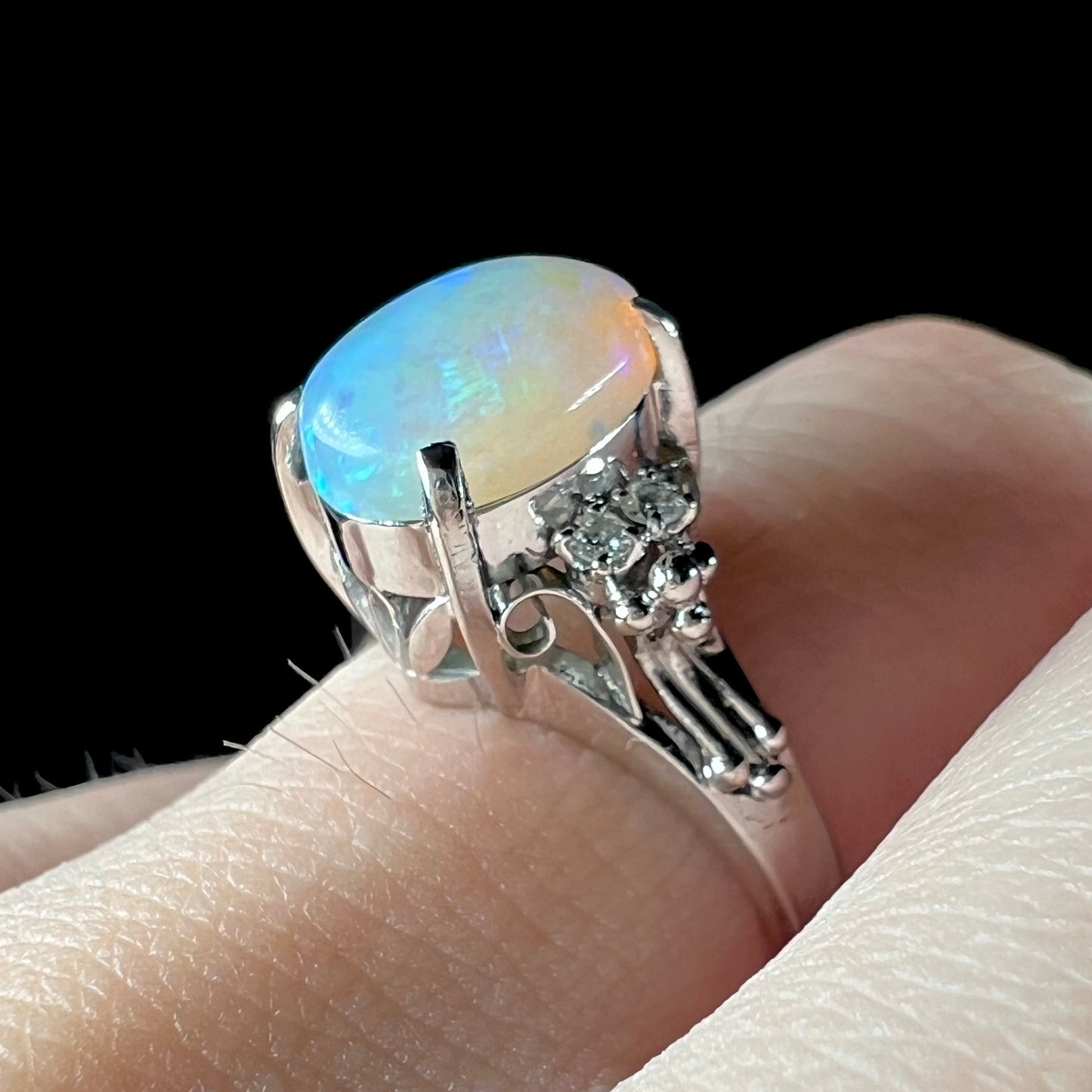 A platinum filigree ring mounted with a blue-green crystal opal and diamond accents.