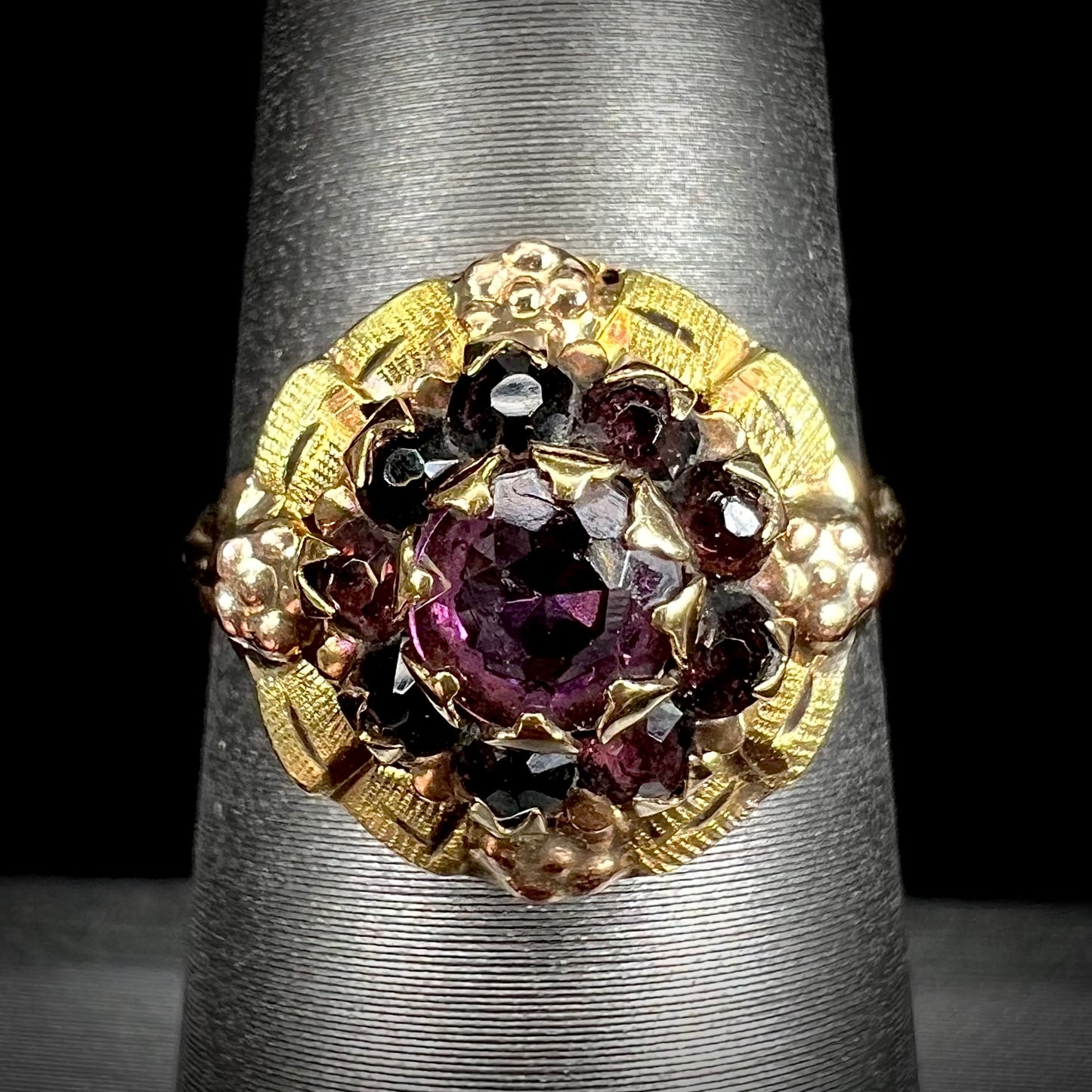 A ladies' Art Nouveau style rhodolite garnet halo ring.  Rose gold flowers accent the piece.